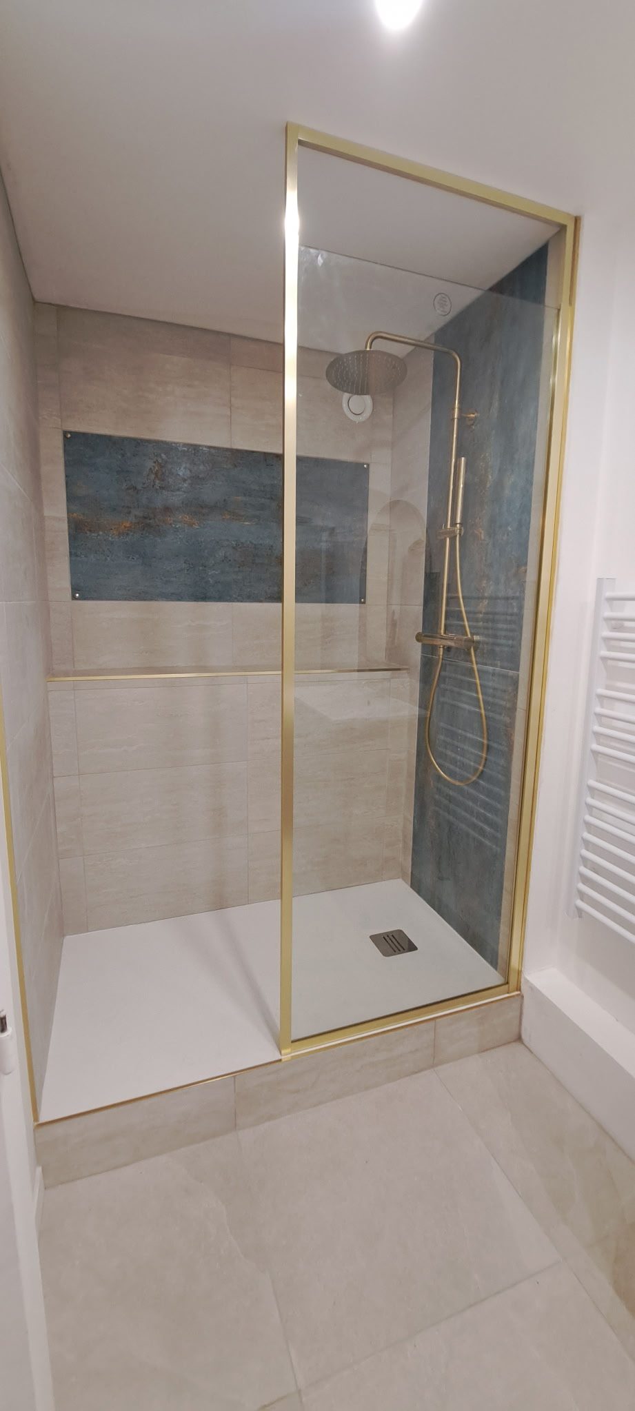 La douche terminée, parois dorées et carrelage minéral